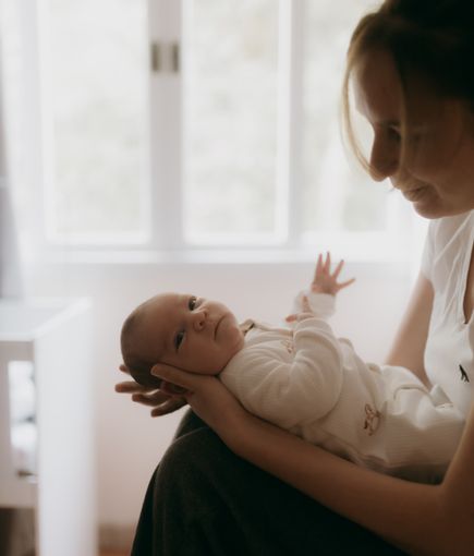 A tender moment between a mother and her baby in a softly lit room, conveying love and warmth.