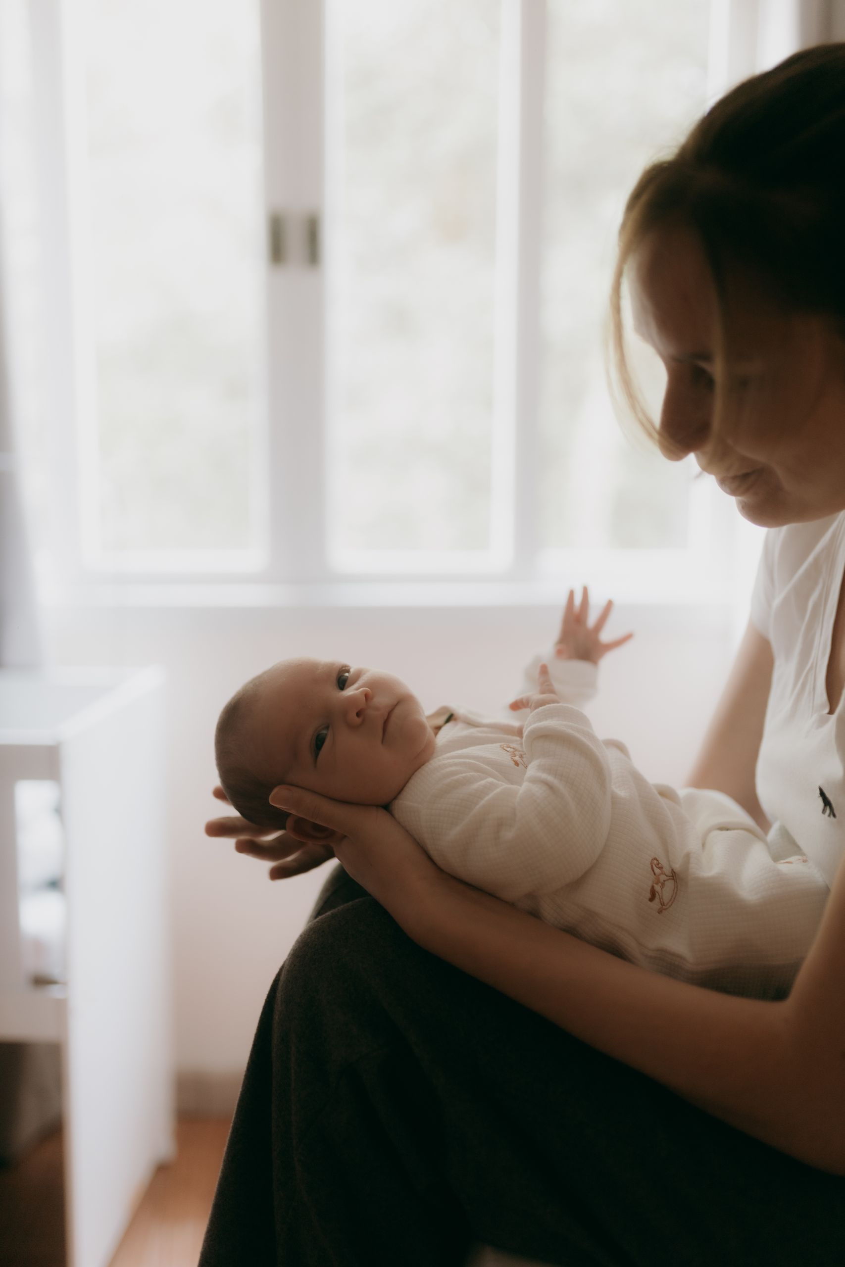 A tender moment between a mother and her baby in a softly lit room, conveying love and warmth.